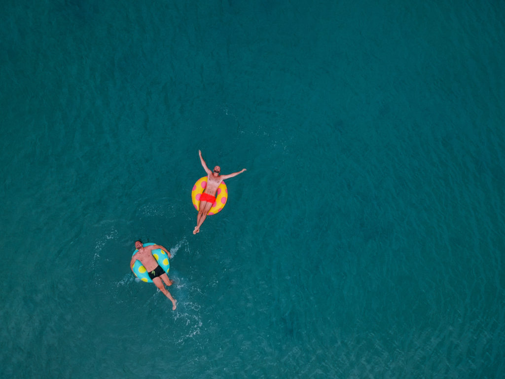 Aerial view of couple relaxing on inflatable rings and floating in the water.