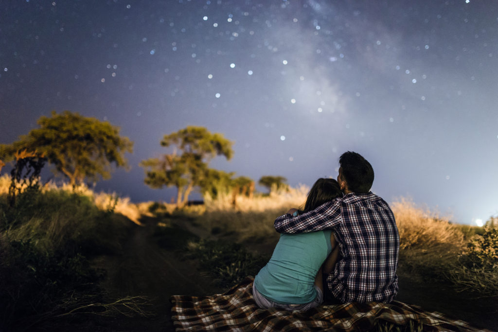 Young people in love under stars of Milky Way Galaxy.