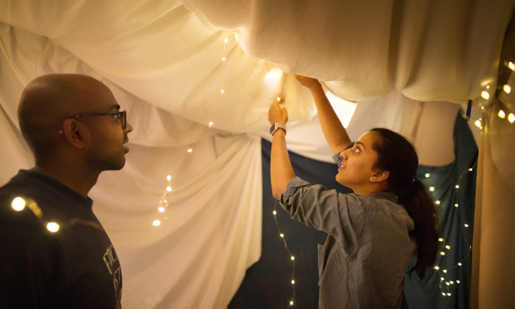 Young people adding lights to a tent made in their living room