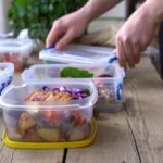 Young person placing single portions of food into containers to meal prep for the coming week