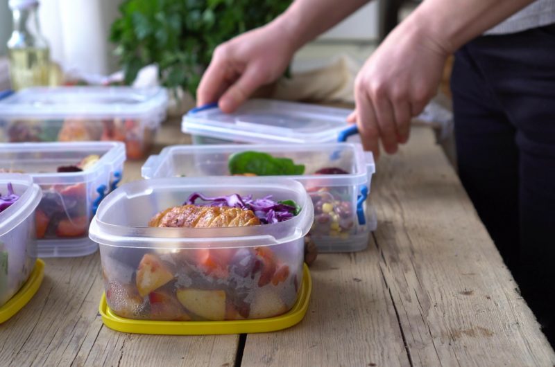 Young person placing single portions of food into containers to meal prep for the coming week