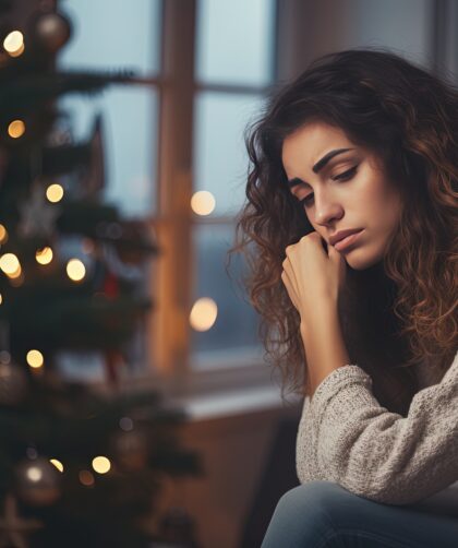 Sad woman sitting in front of a christmas tree