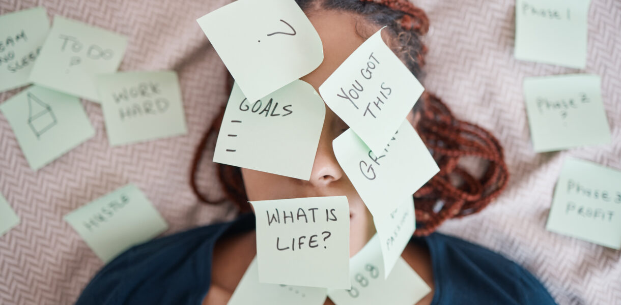 Woman laying in bed with her face covered in sticky notes questioning life