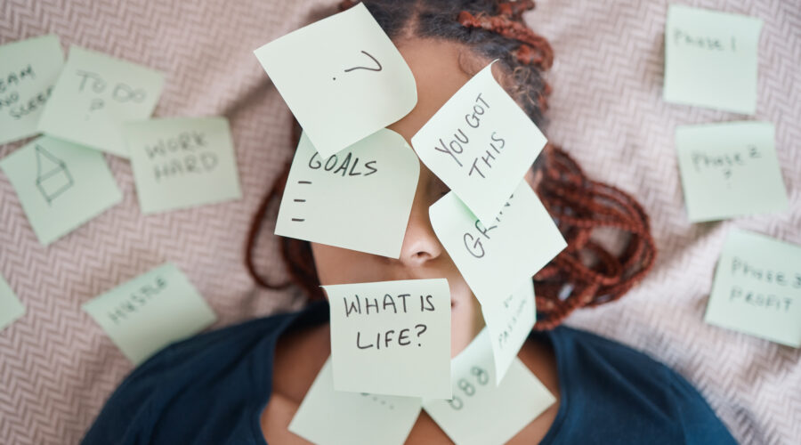 Woman laying in bed with her face covered in sticky notes questioning life