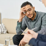 Young man leaning head against hand at therapist's office