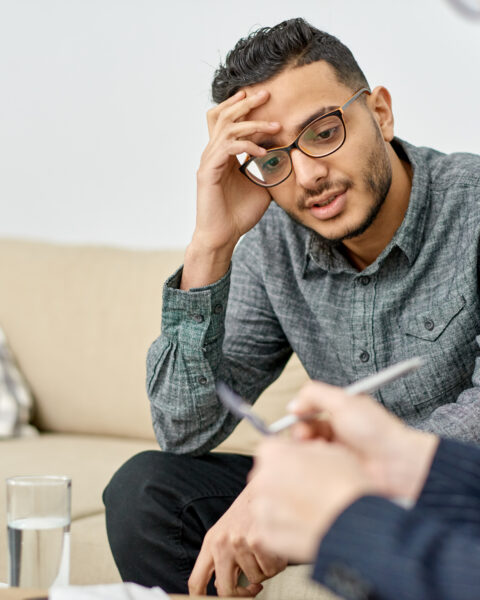 Young man leaning head against hand at therapist's office