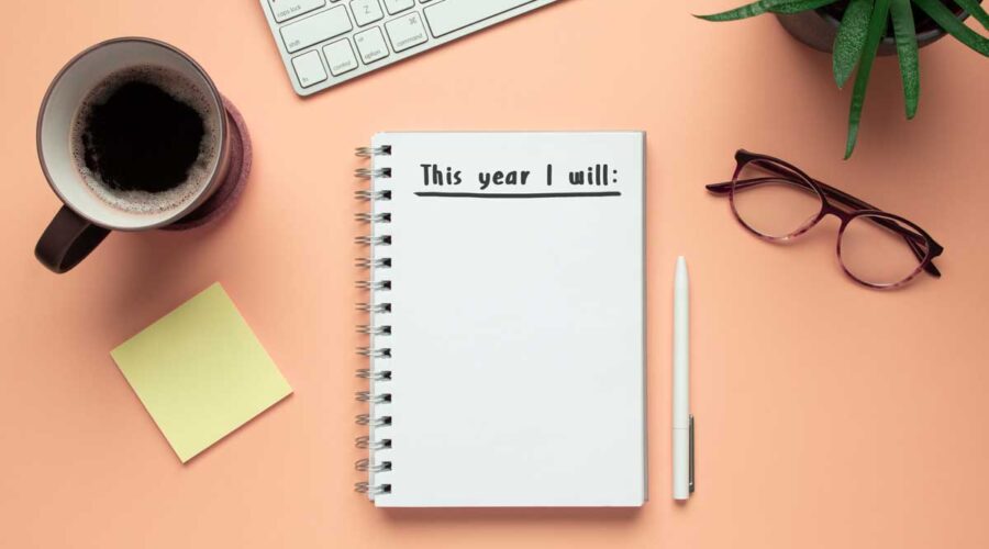 new year notebook with list of resolutions and objects on pink background