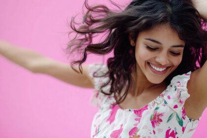 A woman smiles while holding her hair up, capturing a moment of joy.